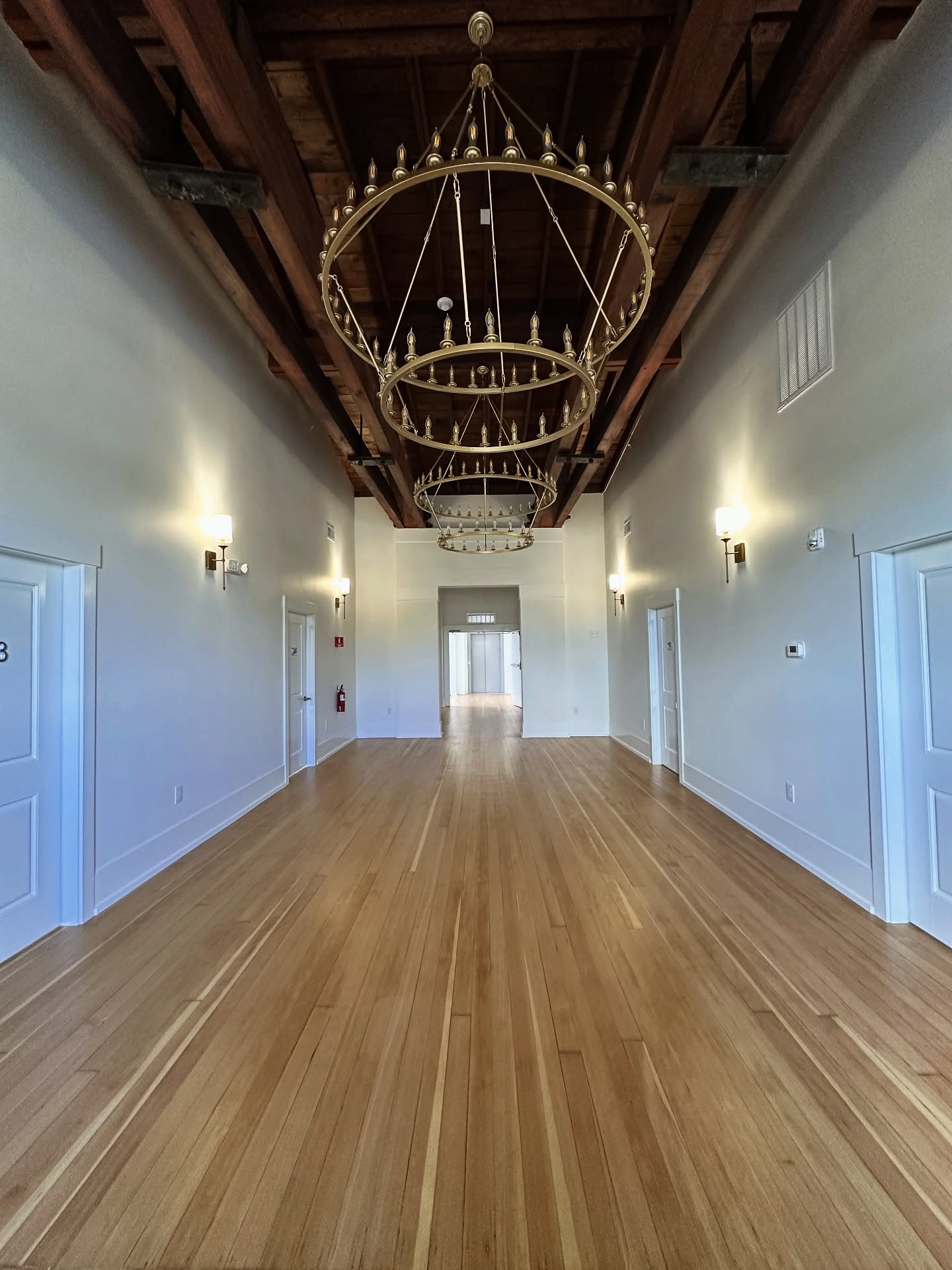 Large hall with exposed wood beam ceiling and refinished wide plank floor
